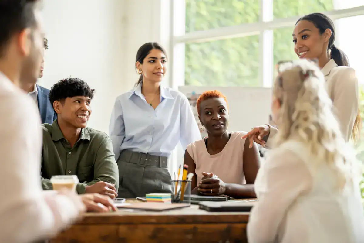 A team of professionals from diverse backgrounds working together in a well-lit office space, illustrating cooperation, teamwork, and creative brainstorming in a professional business setting.