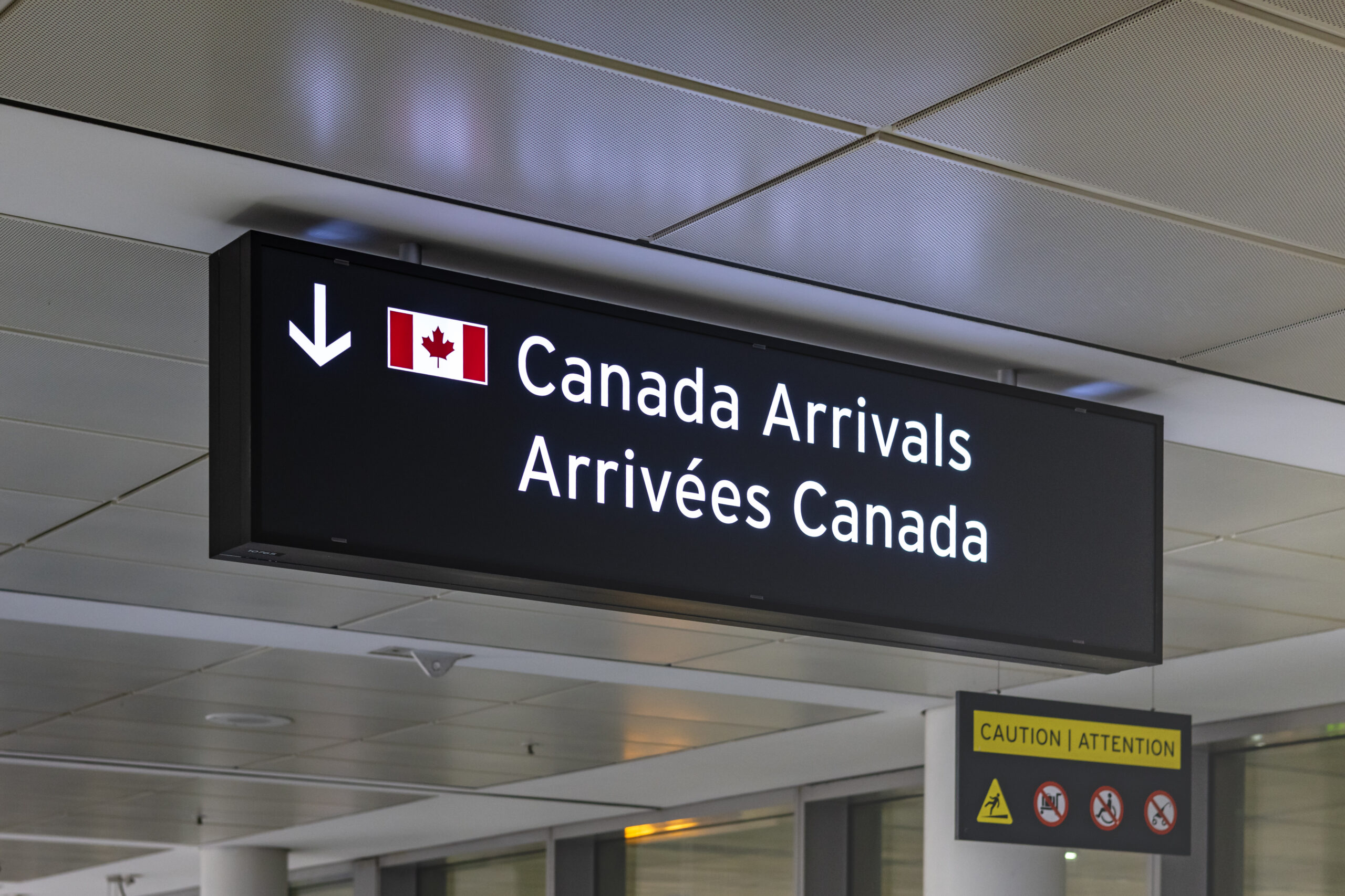 Airport sign indicating Canada Arrivals in English and French with an image of the Canadian Flag