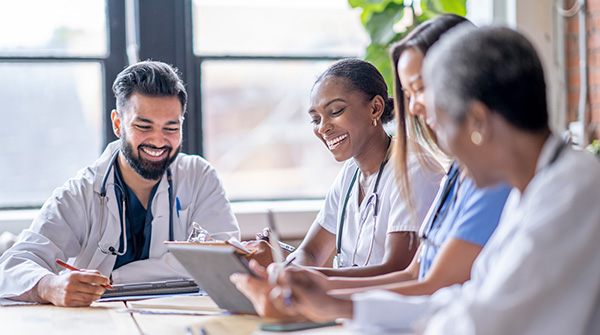 A group of medical professionals discuss a report around a table.