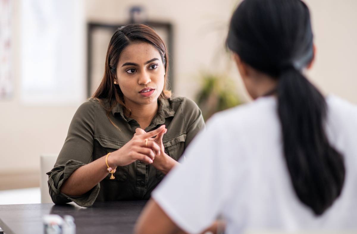 A young woman of Indian descent, sits with her immigration counselor in her office as they discuss her credential evaluation.