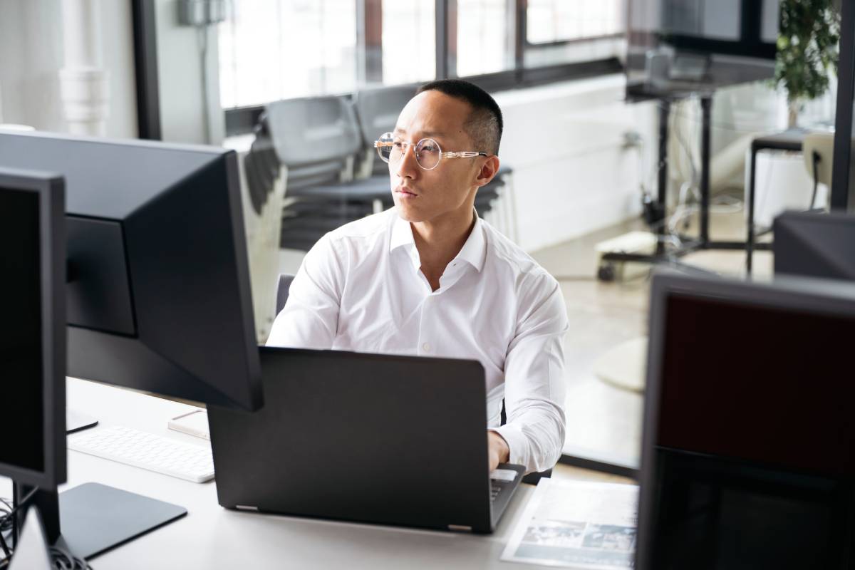 Mid adult Taiwanese business manager wearing white shirt siting at desk, working, concentration, focus, efficiency