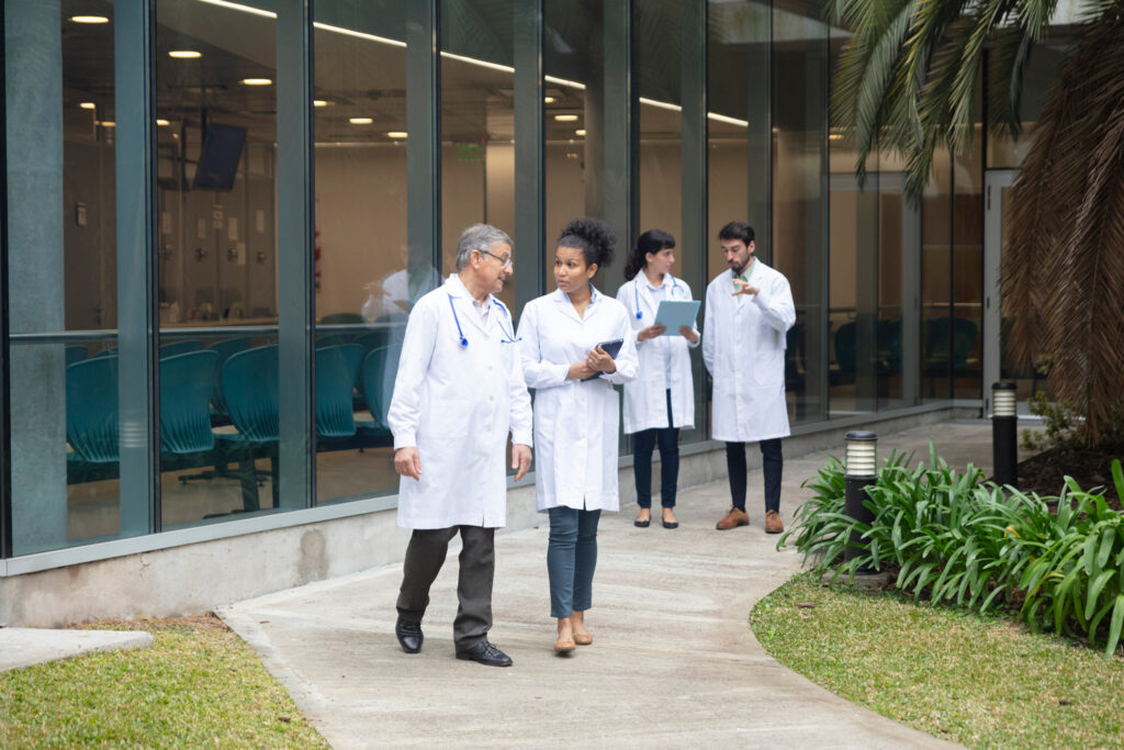 A group of internationally trained physicians walks through a hospital garden.